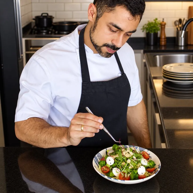 Chef finalizando um prato com pinça na cozinha do Container